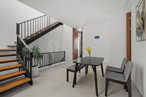 A modern interior with a staircase, a dining table with chairs, and a potted plant. - Anaya Villa by Kozystay - Paskal (Bandung)