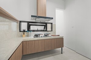 A modern kitchen with a built-in stove, a range hood, and a window above the sink. - Anaya Villa by Kozystay - Paskal (Bandung)