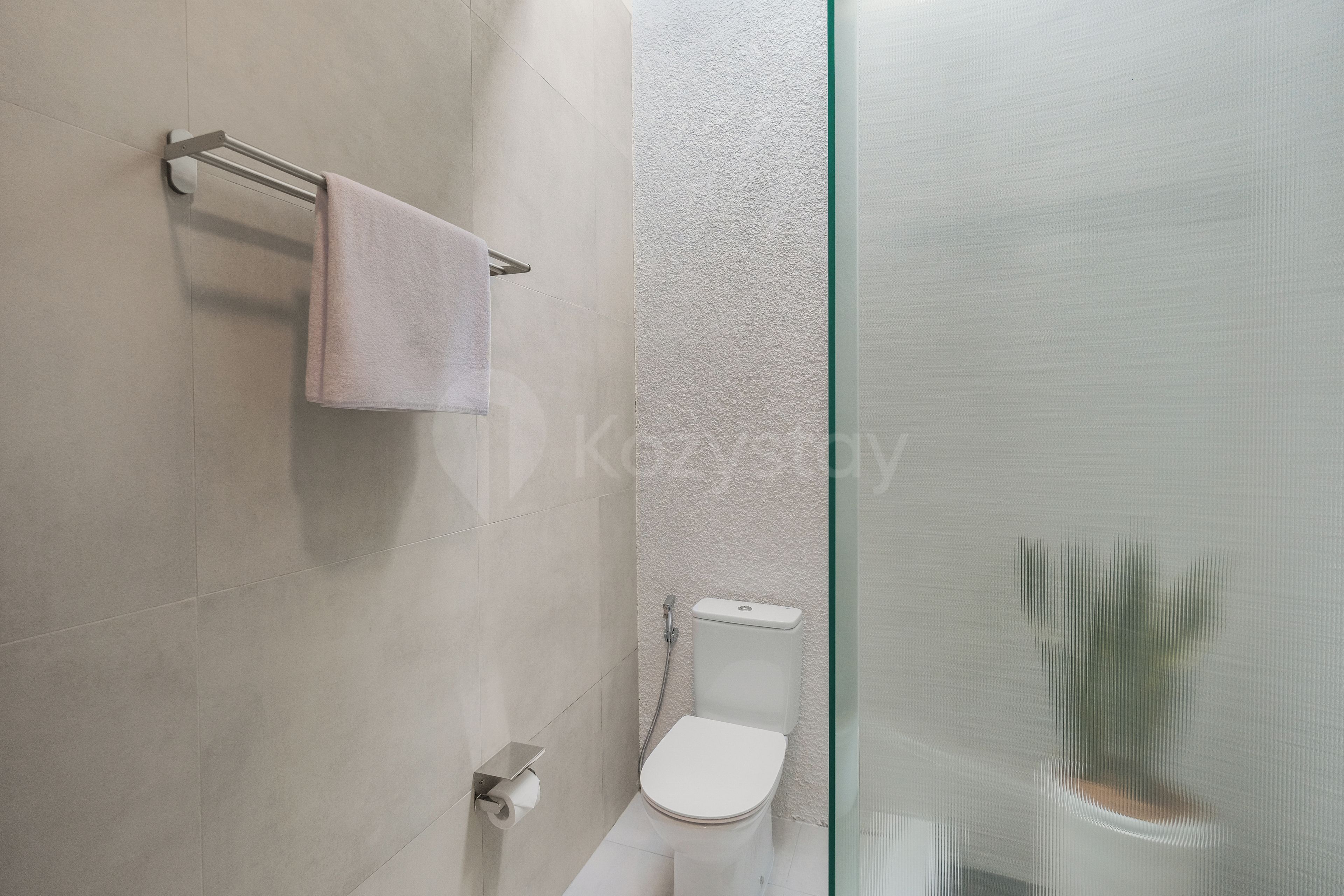 Un baño moderno con cabina de ducha de vidrio, inodoro y barra para toallas.