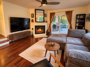Una sala de estar con televisión de pantalla plana, chimenea, sofá y vistas al exterior.