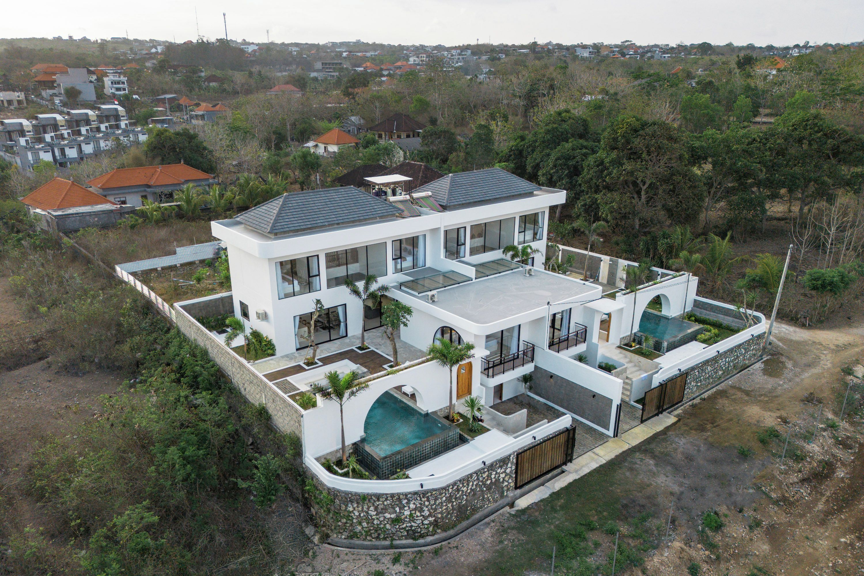 Uma casa moderna de dois andares com uma varanda grande e piscina.
