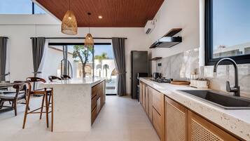 Una cocina moderna con una isla central, armarios de madera, un lavamanos de acero inoxidable y vistas al exterior.