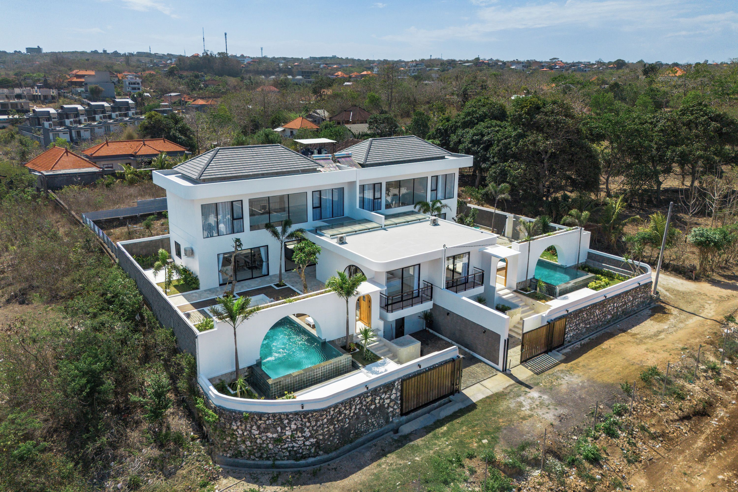 A modern two-story house with a swimming pool, surrounded by a natural landscape.