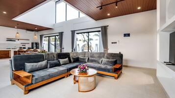 Una sala moderna con un sofá modular, una mesa de centro y un comedor con una cocina al fondo.
