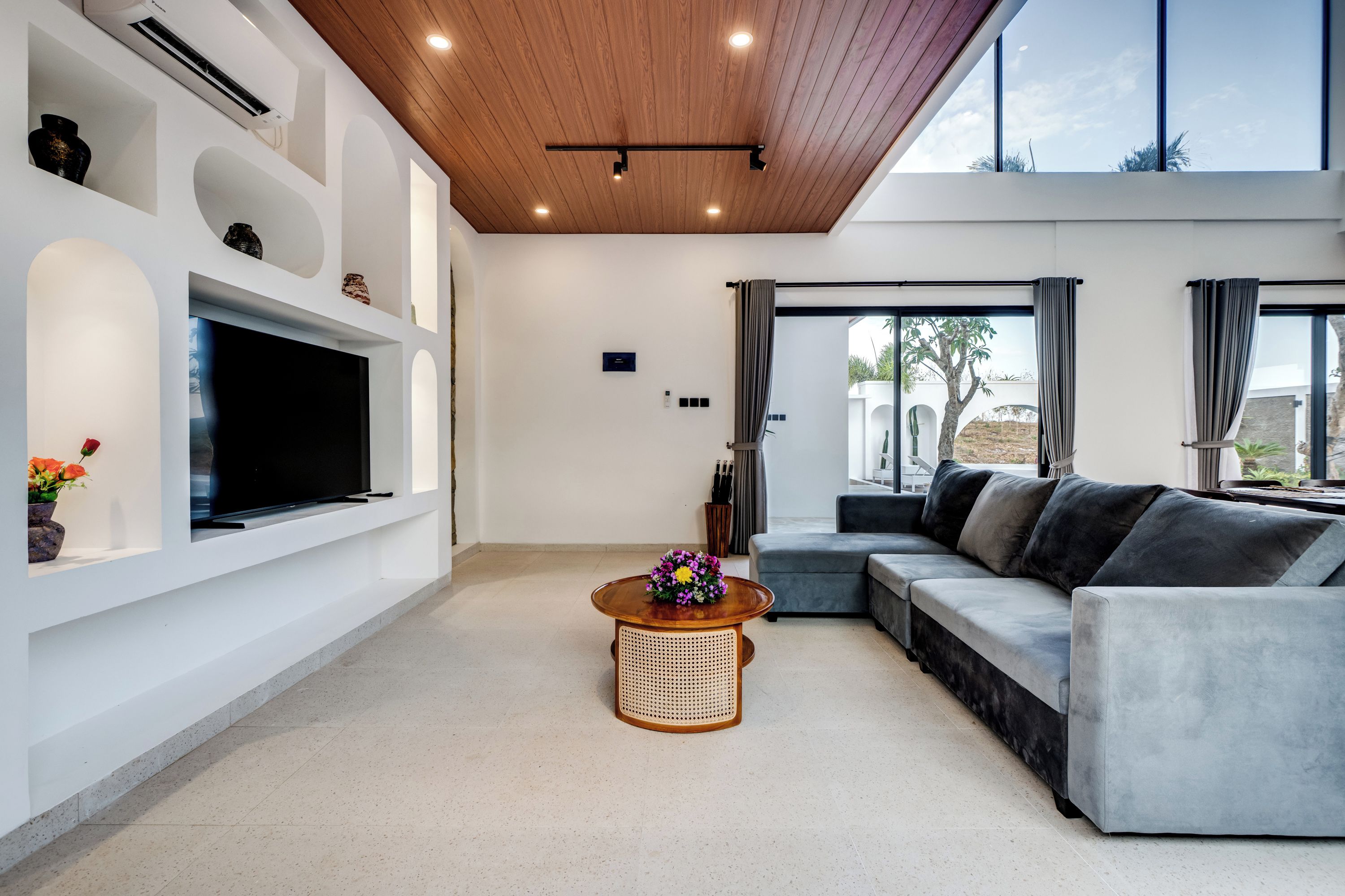 A modern living room with a flat-screen TV, a sofa, a coffee table, and a large window.