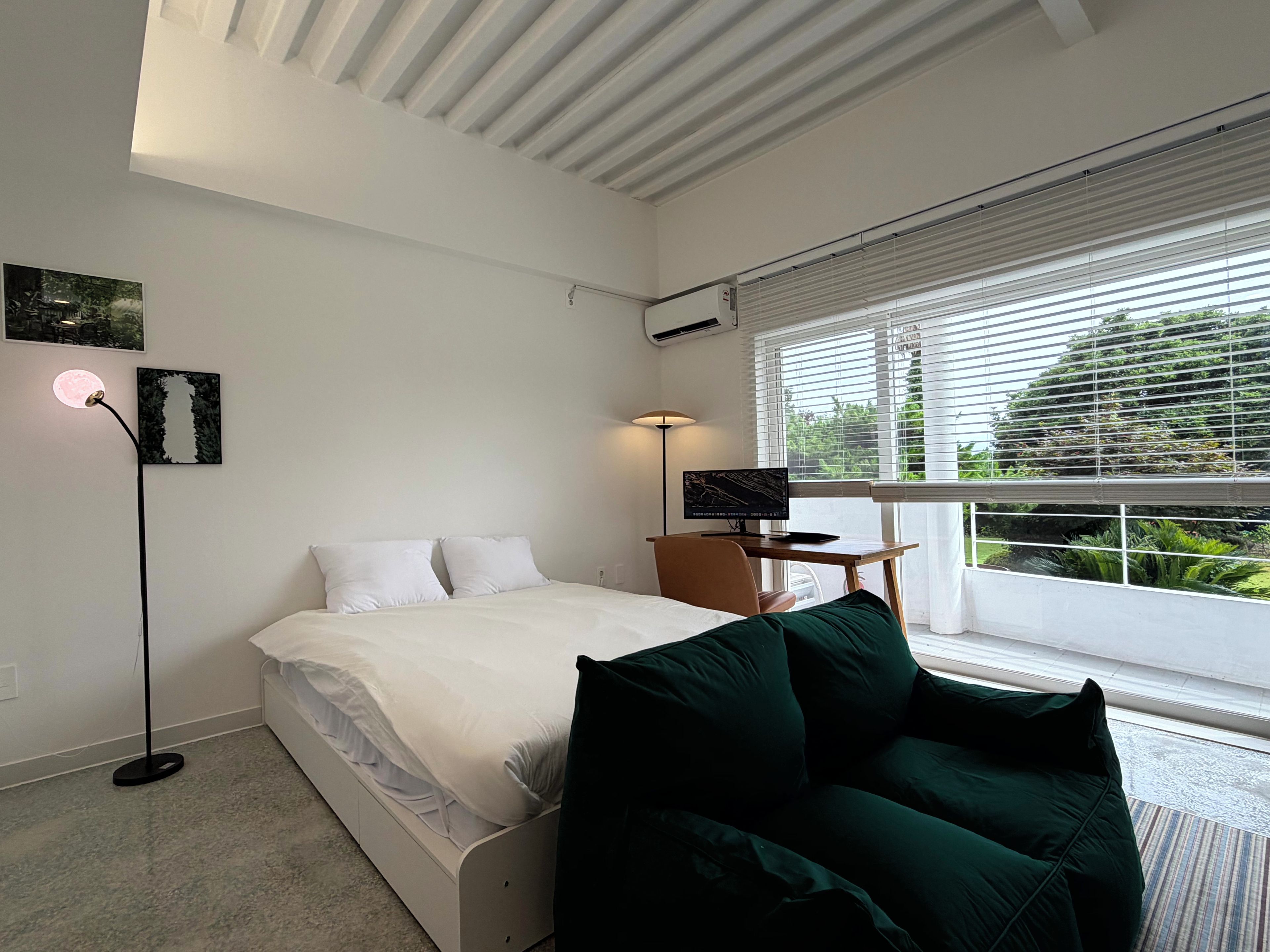 Un dormitorio con cama, escritorio, silla y ventana con persianas.