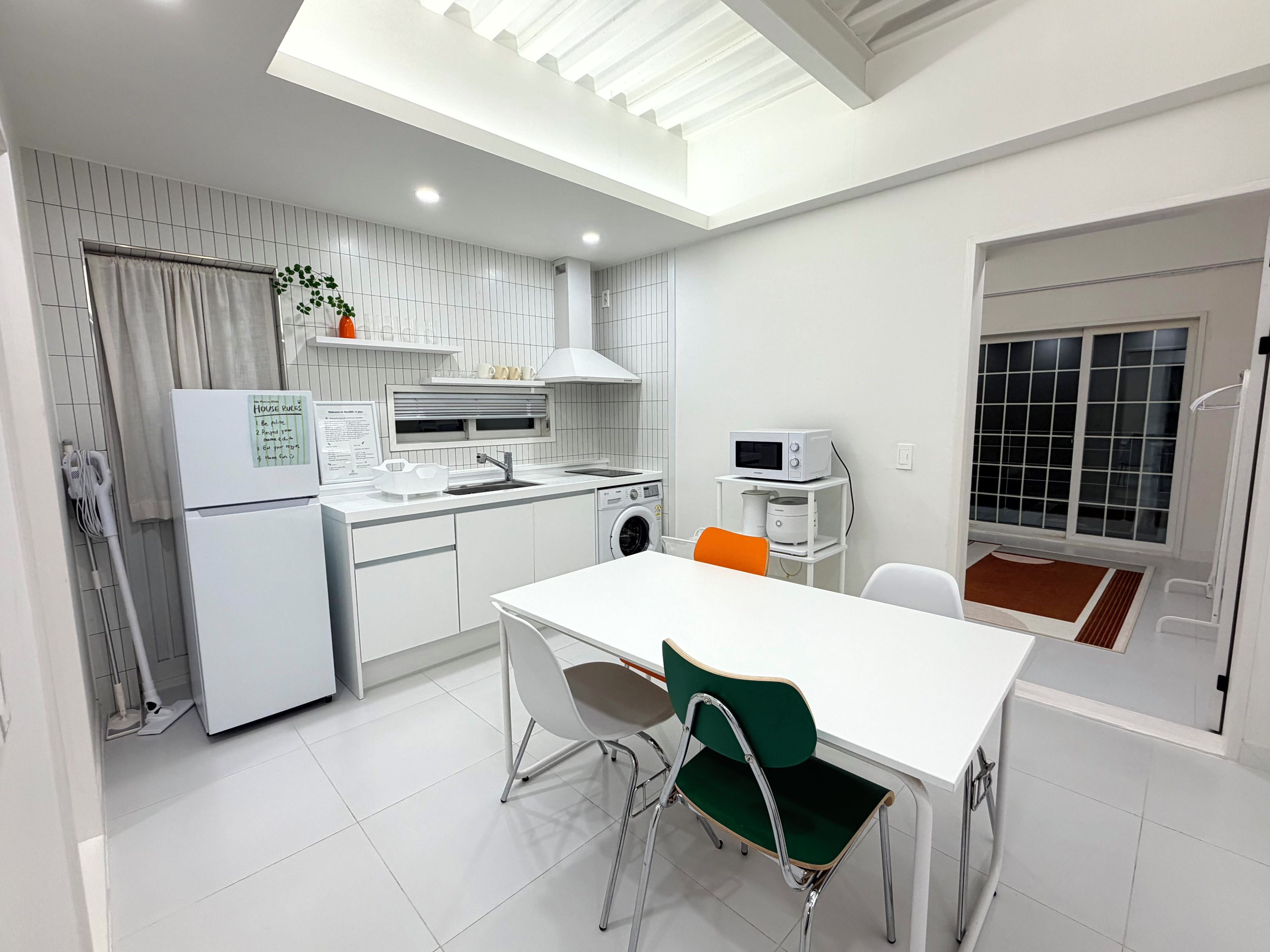 Une cuisine moderne avec un coin repas, comprenant un réfrigérateur, un four à micro-ondes, un évier et une table avec des chaises.