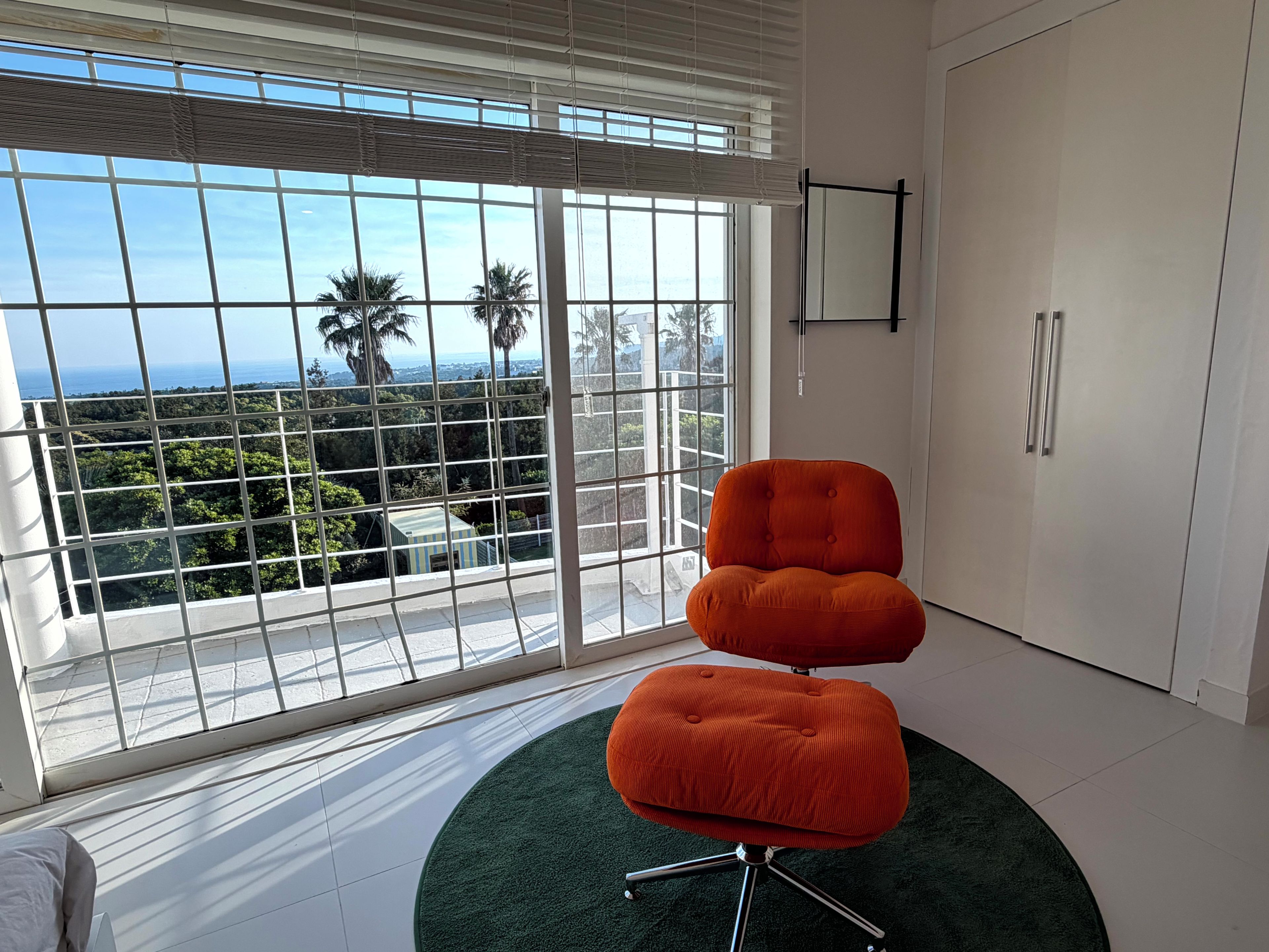 A room with a large window, a chair, and a door.