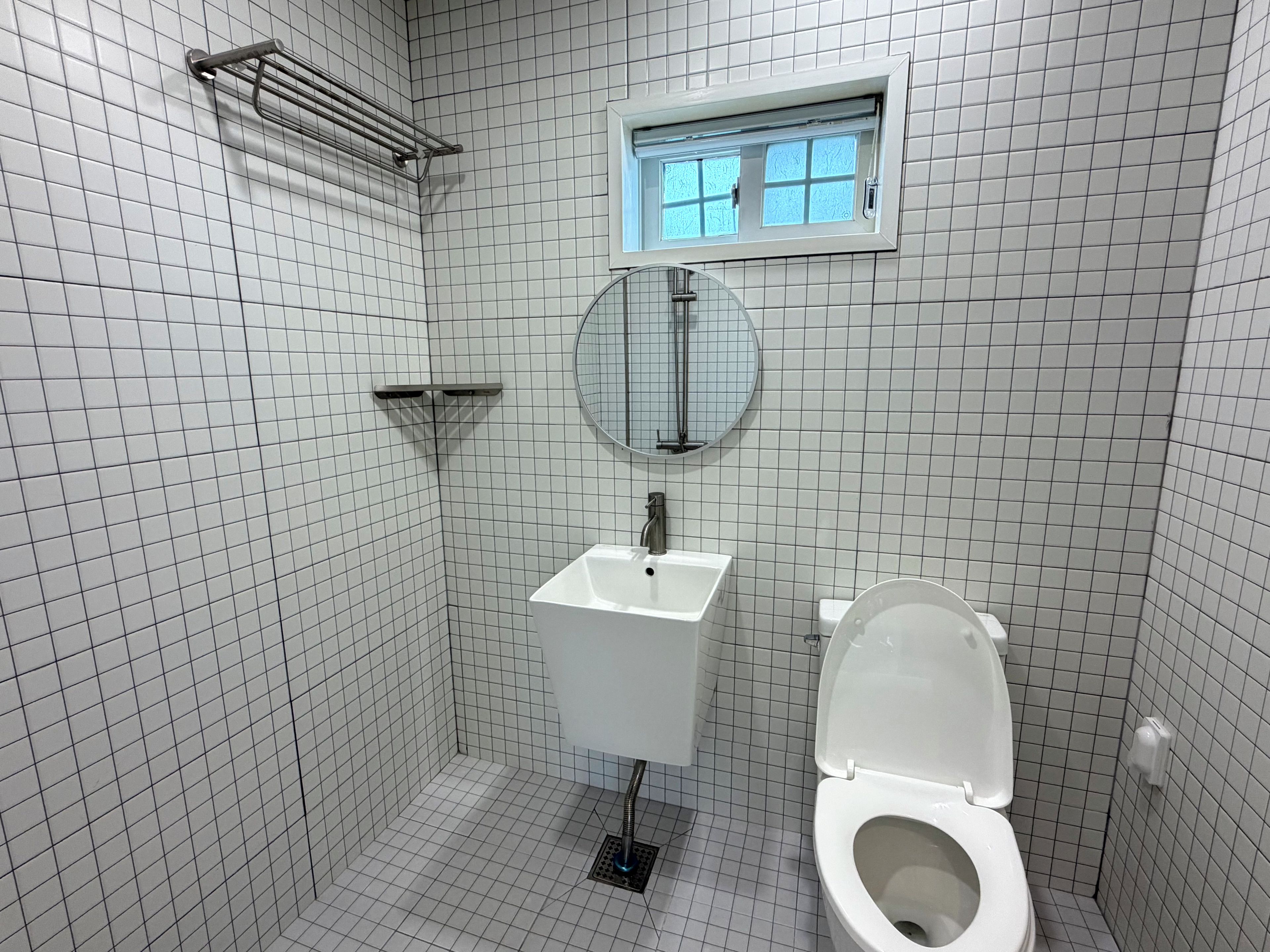 Un bagno con pavimento piastrellato bianco, un lavandino bianco con specchio sopra e un water.