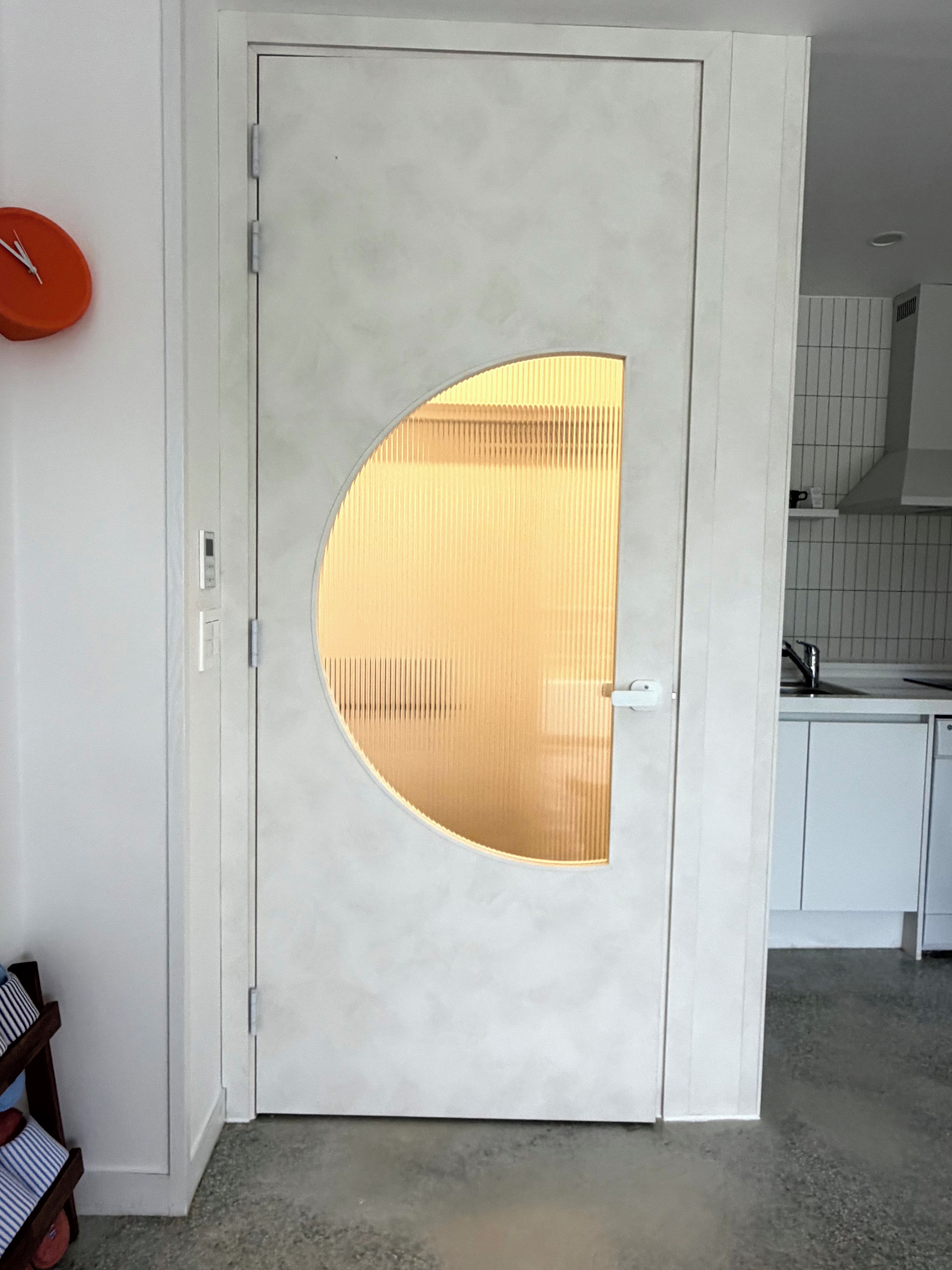A white door with a semi-circular glass panel.