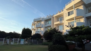 Un edifici residencial de diverses plantes amb balcons, un pati tancat i diferents tipus d'arbres.