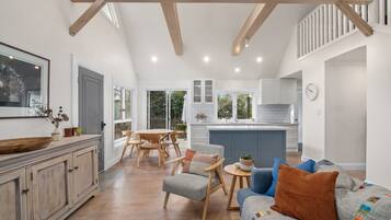 A spacious living area with a dining table, a sofa, and a kitchen in the background.