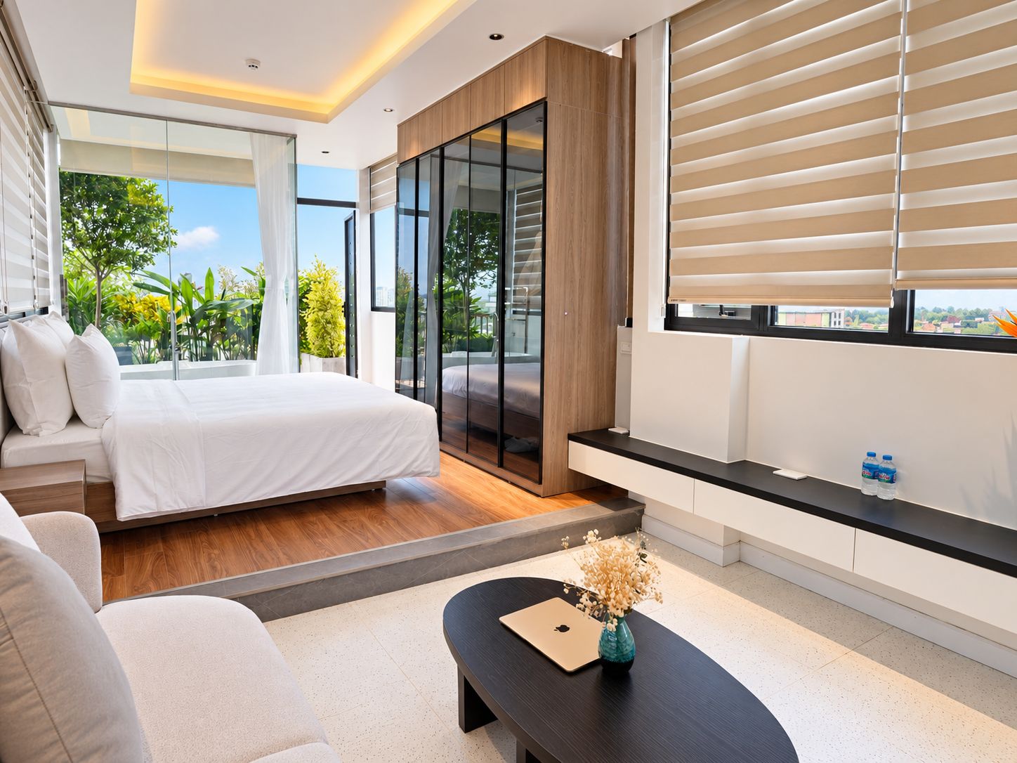 Een moderne slaapkamer met een bed, een slaapbank, een bijzettafeltje en uitzicht op groen.