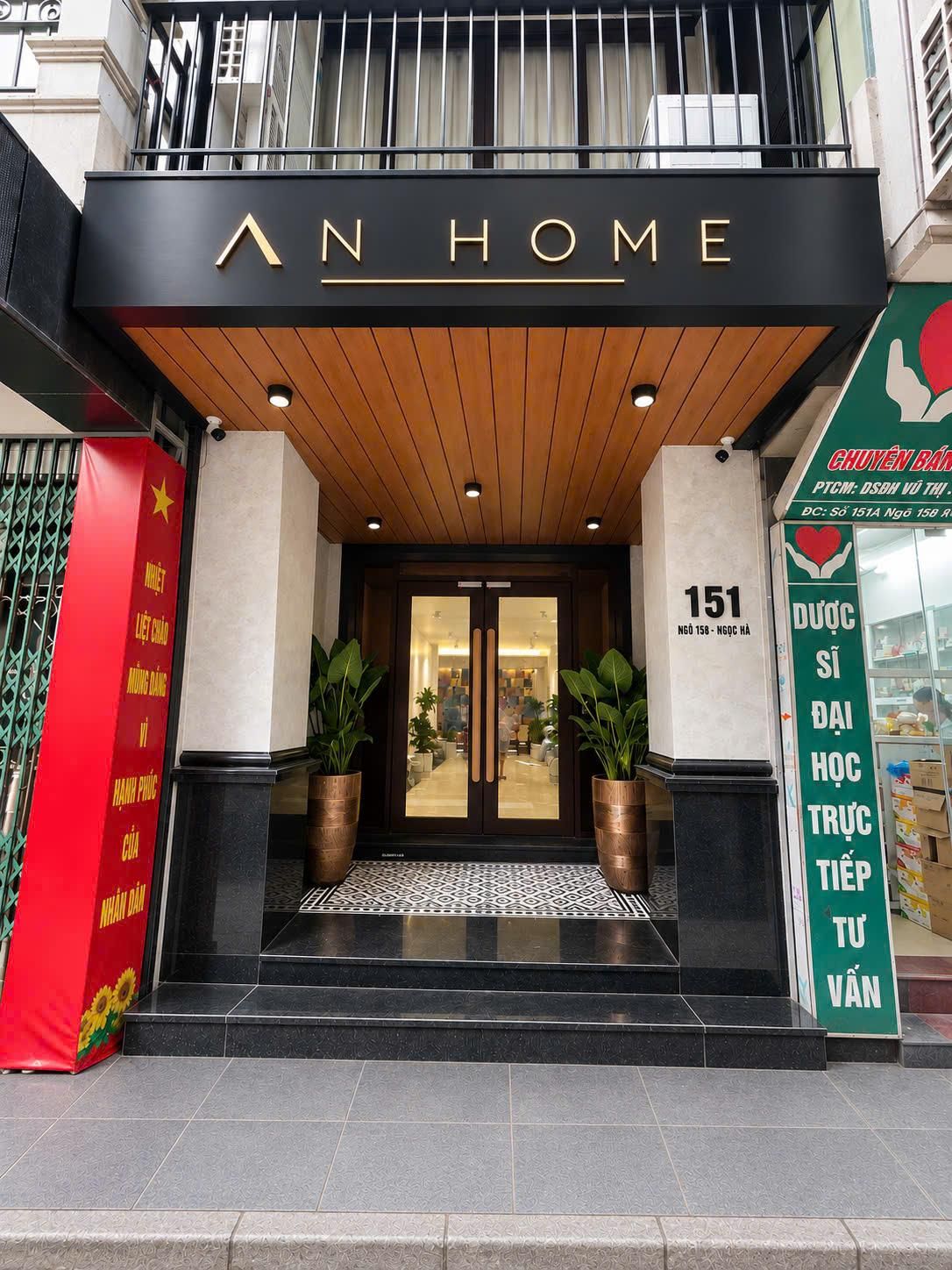 En hotelindgang med et skilt, der viser 'AN HOME' og adressen '151'.