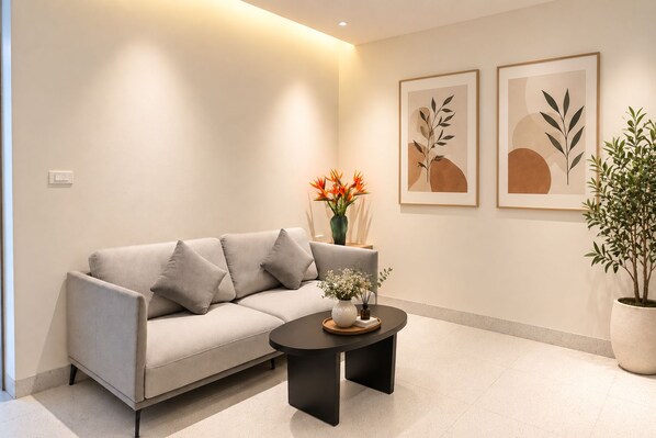 A modern living room with a sofa, a coffee table, and two framed artworks on the wall.