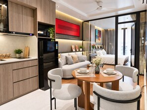 A modern kitchen with a black refrigerator, a dining area with a round table and four chairs, a sofa, and a large window with curtains. - An Home (Ngoc Ha)