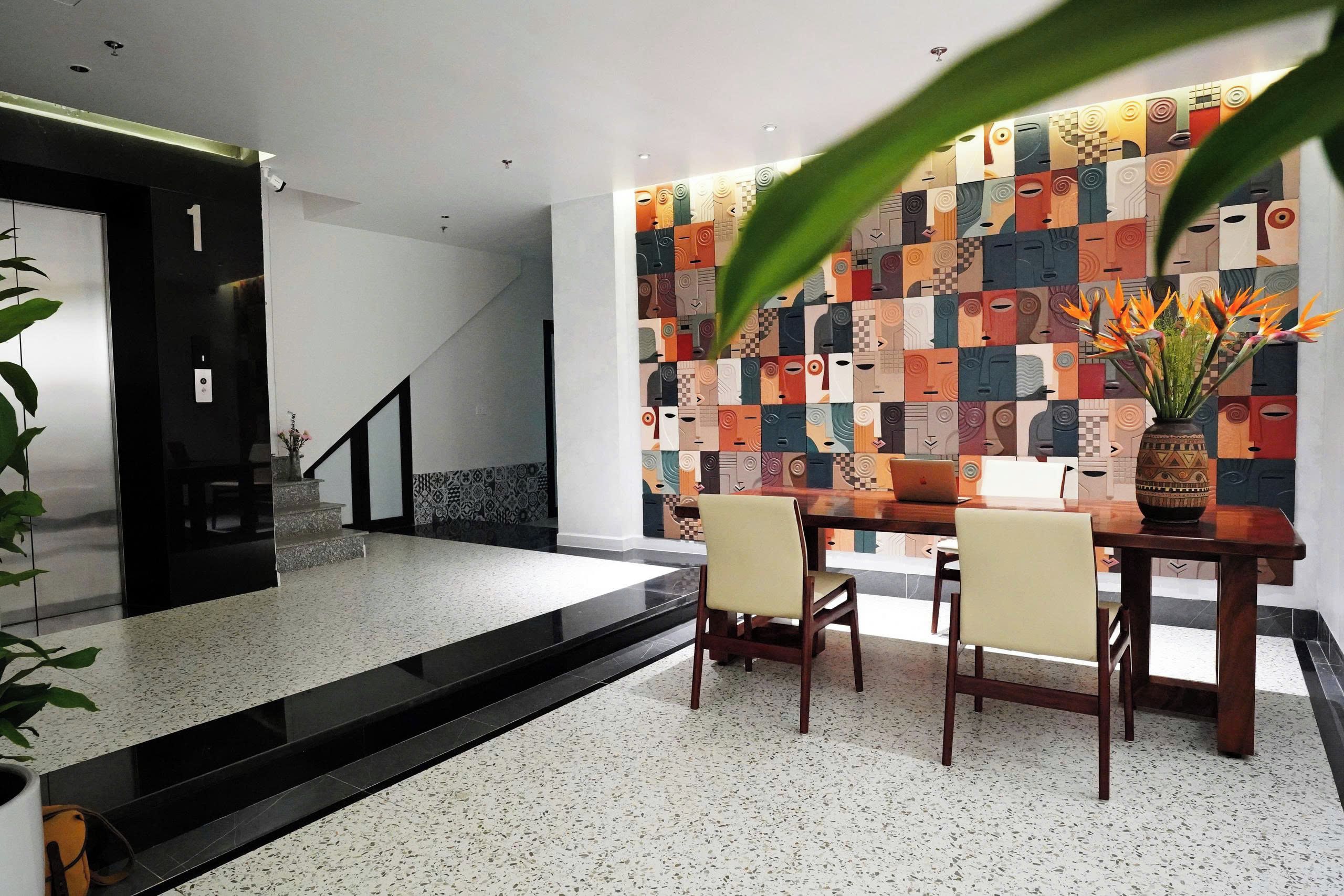 A hotel lobby with a staircase, a reception desk, and a wall with a geometric pattern.