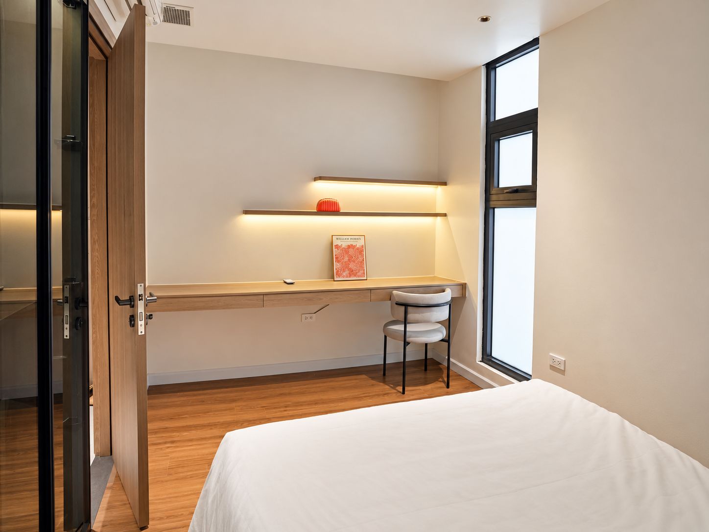 Quarto com uma cama, uma escrivaninha com cadeira, janela e porta.