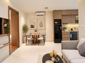 A modern living room with a sofa, a dining area with a table and chairs, and a kitchen with appliances. - An Home (Ngoc Ha)