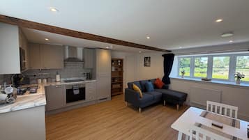 A modern kitchen with built-in appliances, a dining area with a white table, and a large window with a view.
