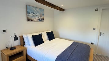 A bedroom with a bed, bedside table, lamp, and a painting on the wall.