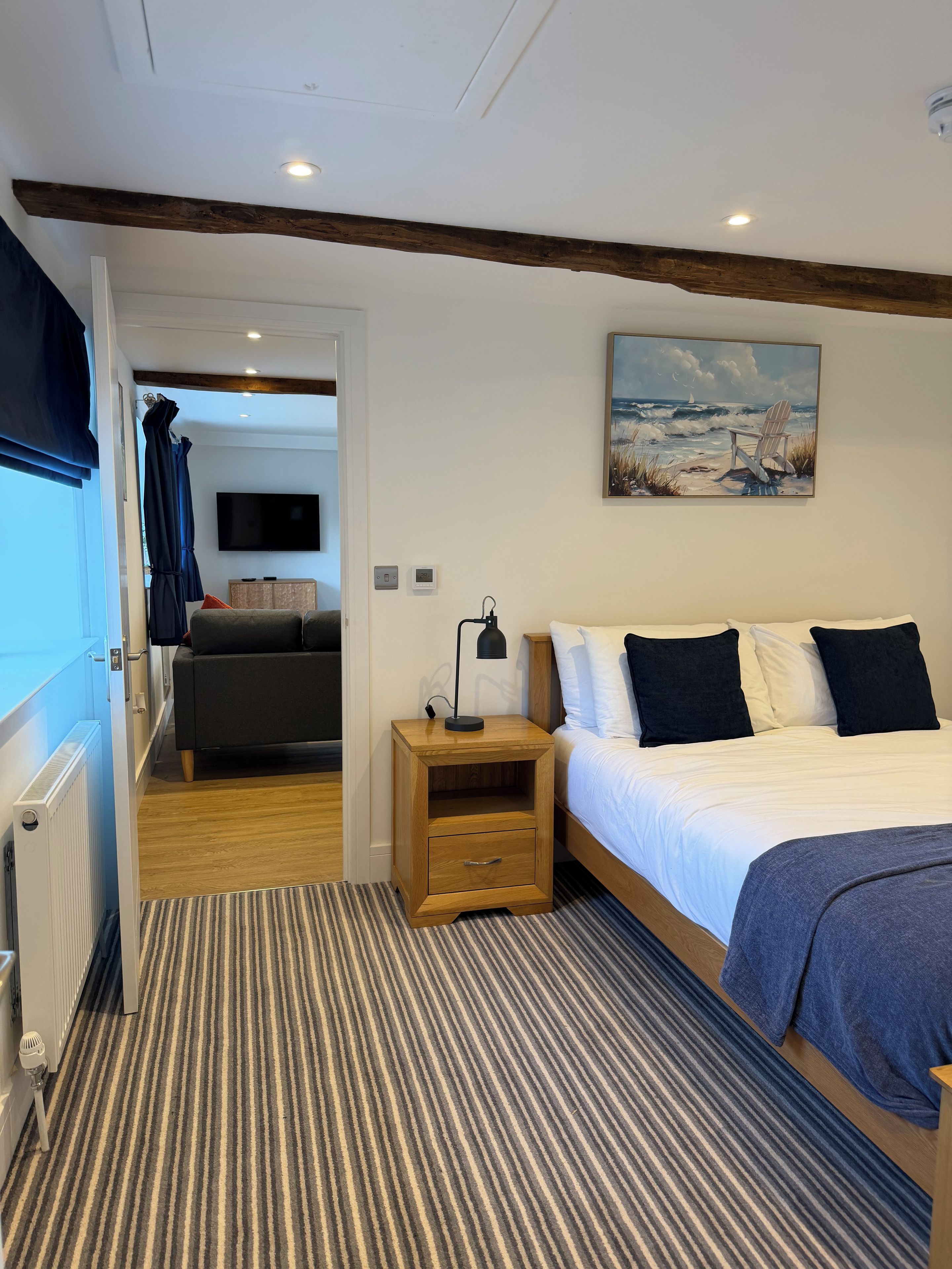 Un dormitorio con una cama, mesita de noche y un cuadro en la pared.