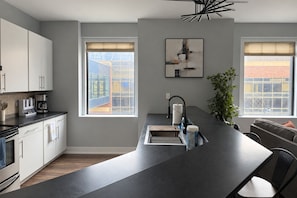 Una cocina moderna con una isla central, electrodomésticos integrados y ventanas amplias con vistas al exterior.