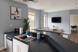 A modern kitchen with a built-in island, a dining area with a table, and a living space with a TV.
