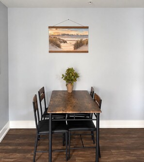 A dining area with a wooden table, four chairs, and a potted plant.
