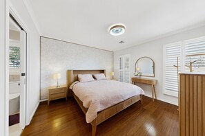 Un dormitorio con cama, mesitas de noche, un espejo y un aparador.