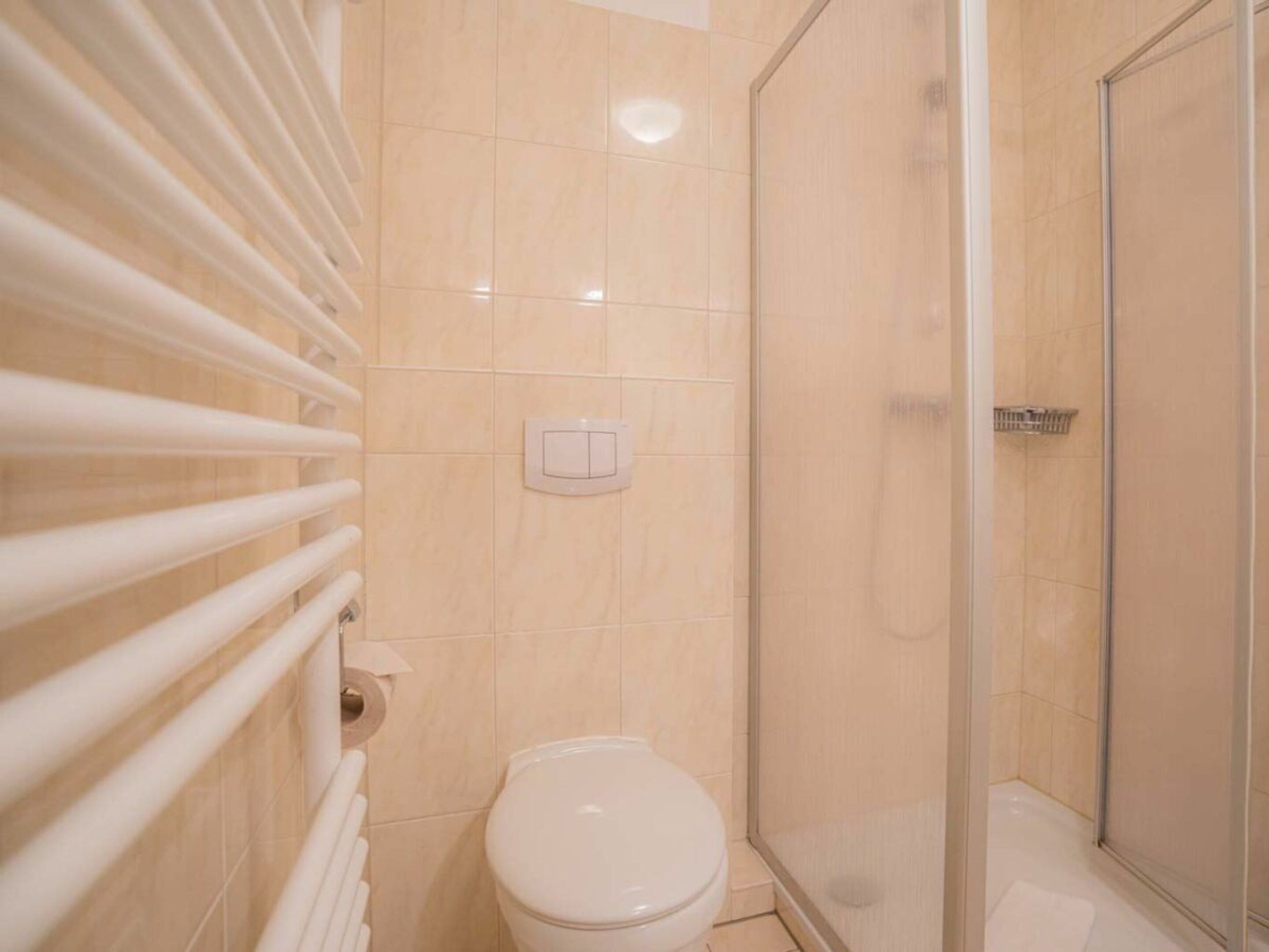 A bathroom with a toilet, a shower enclosure, and a towel rack.