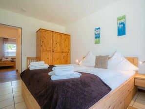 Ein Schlafzimmer mit einem hölzernen Bett, weißen Leinen, einer braunen Decke und einem Holzschrank.