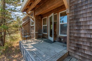 A wooden cabin with a porch, two chairs, and a table. - The Little Mermaid - Dogs OK - Minutes to beach (Pacific City)
