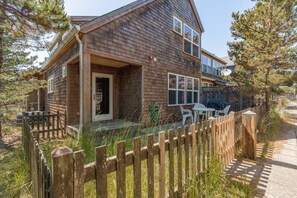 A wooden cabin with a porch, a fenced yard, and outdoor furniture. - The Little Mermaid - Dogs OK - Minutes to beach (Pacific City)