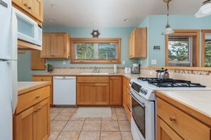 Une cuisine avec des meubles en bois, une cuisinière blanche, un four à micro-ondes et un lave-vaisselle.