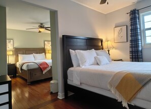 Habitación de hotel con una cama grande, una cama más pequeña, un ventilador de techo y una ventana con cortinas.