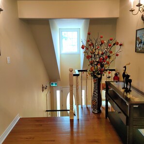 Una escalera con barandilla de madera, un florero con flores y un candelabro.