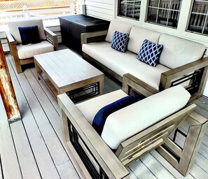 A wooden deck with outdoor furniture including a sofa, two chairs, and a table. - L&V | Victorian Garden Retreat | 3BR| Spacious Deck | Walk to Historic Old Town (Niagara-on-the-Lake)