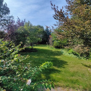 A well-maintained grassy area with trees and shrubs, likely part of a garden or park. - L&V | Victorian Garden Retreat | 3BR| Spacious Deck | Walk to Historic Old Town (Niagara-on-the-Lake)