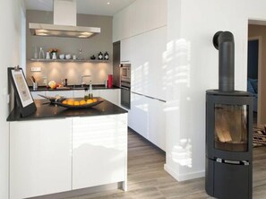 Une cuisine moderne dotée d’un îlot central, d’une cuisinière intégrée et d’un coin repas offrant une vue sur l’extérieur.