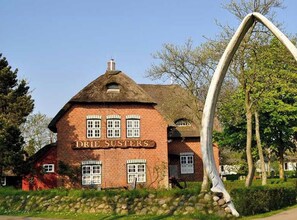 Ein Backsteinhaus mit einem Schild, auf dem 'DRIE SUSTERS' steht.