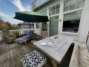 Eine Holzterrasse mit Tisch, Stühlen und Sonnenschirm.
