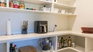 A kitchen with white shelves, a coffee maker, a blender, and various kitchen items.