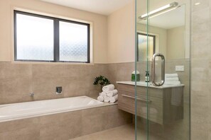 Un baño moderno con bañera, cabina de ducha de vidrio y tocador con espejo.
