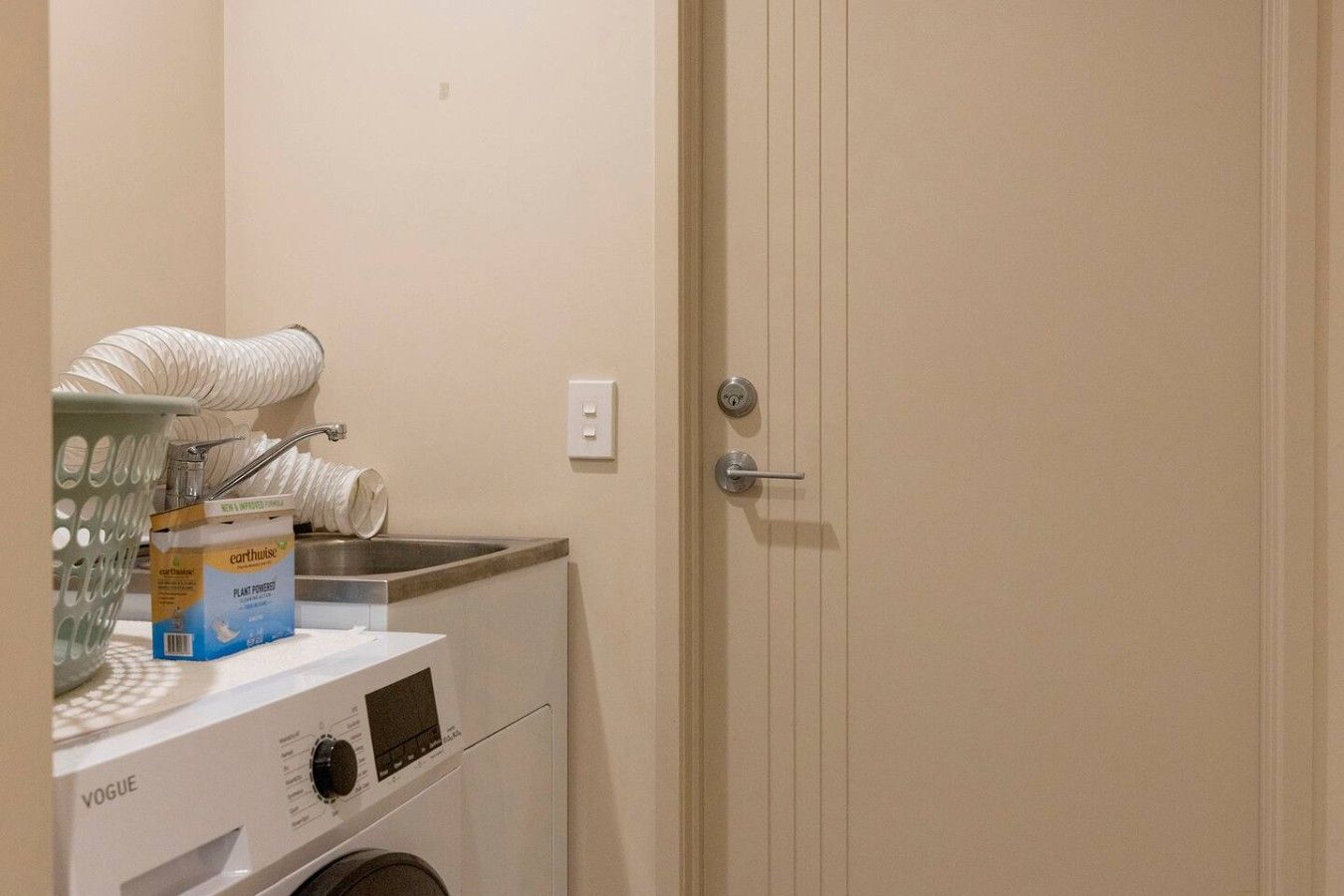 A laundry area with a washing machine, a sink, and a door with a handle.