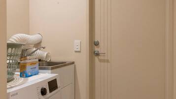 A laundry area with a washing machine, a sink, and a door with a handle.