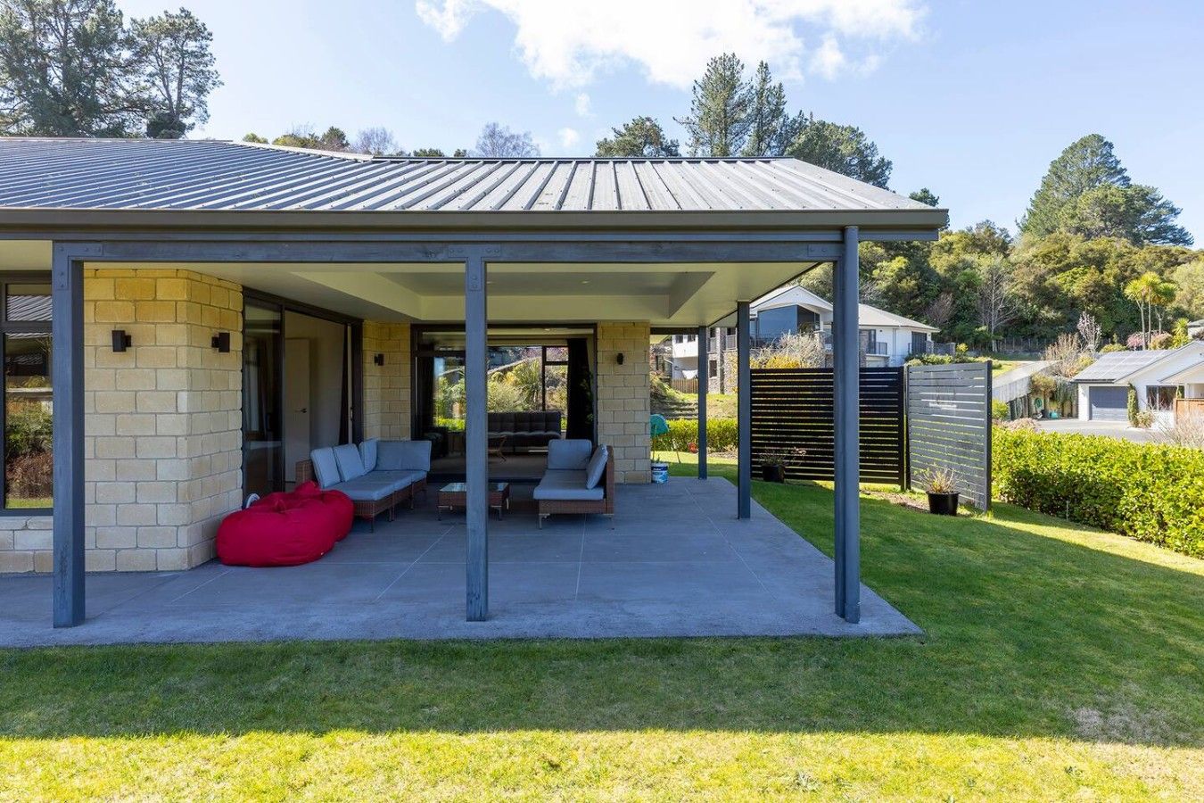 A covered outdoor seating area with a patio, a red bean bag, and a view of the surrounding landscape.