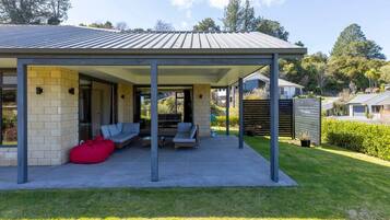 A covered outdoor seating area with a patio, a red bean bag, and a view of the surrounding landscape.