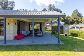 Un espace extérieur abrité avec des sièges, une terrasse, un pouf rouge et une vue sur le paysage environnant.