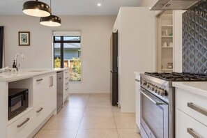A modern kitchen with a built-in oven, a stovetop, and a window with a view of the outdoors.